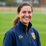 Foto de Sofia Correia, Coordenadora Técnica, sorrindo num campo de futebol.